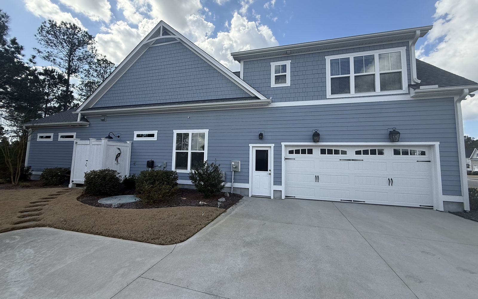 Blue two-story home with white trim and a two-car garage above a clean concrete driveway.