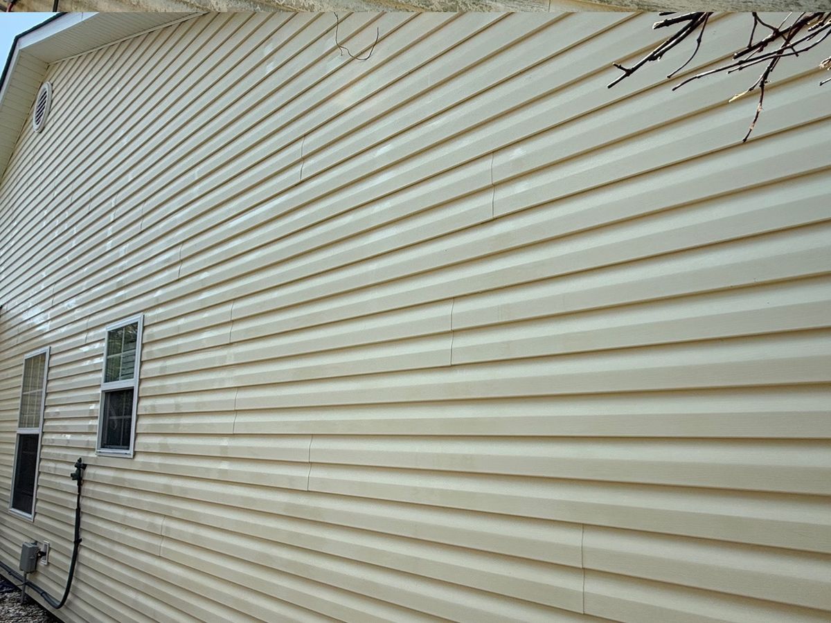 Freshly soft-washed light vinyl siding on the side of a home, clean and even from end to end.